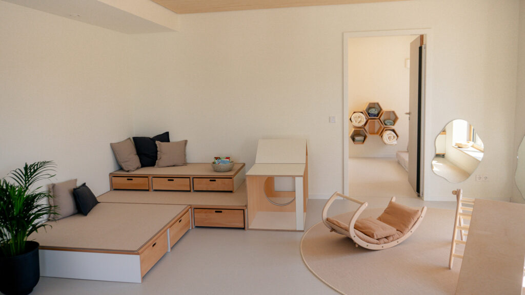 Mehrere Naturholzstämme im Innenraum als Gestaltungselement mit Blick durch eine Glaswand in einen weiteren Raum.